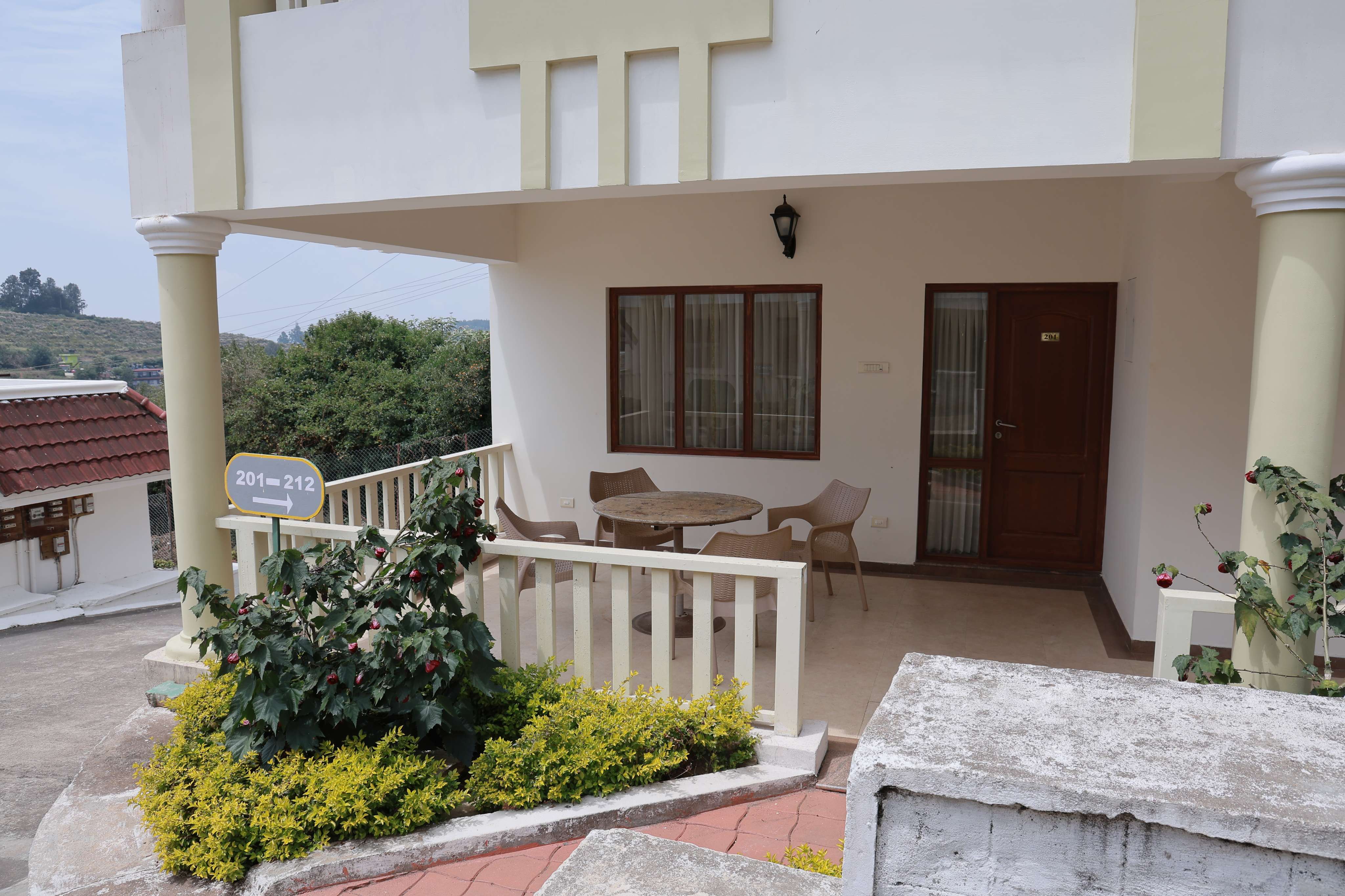 Deluxe hotel room with private patio, outdoor seating, and garden view at a luxury hillside resort.
