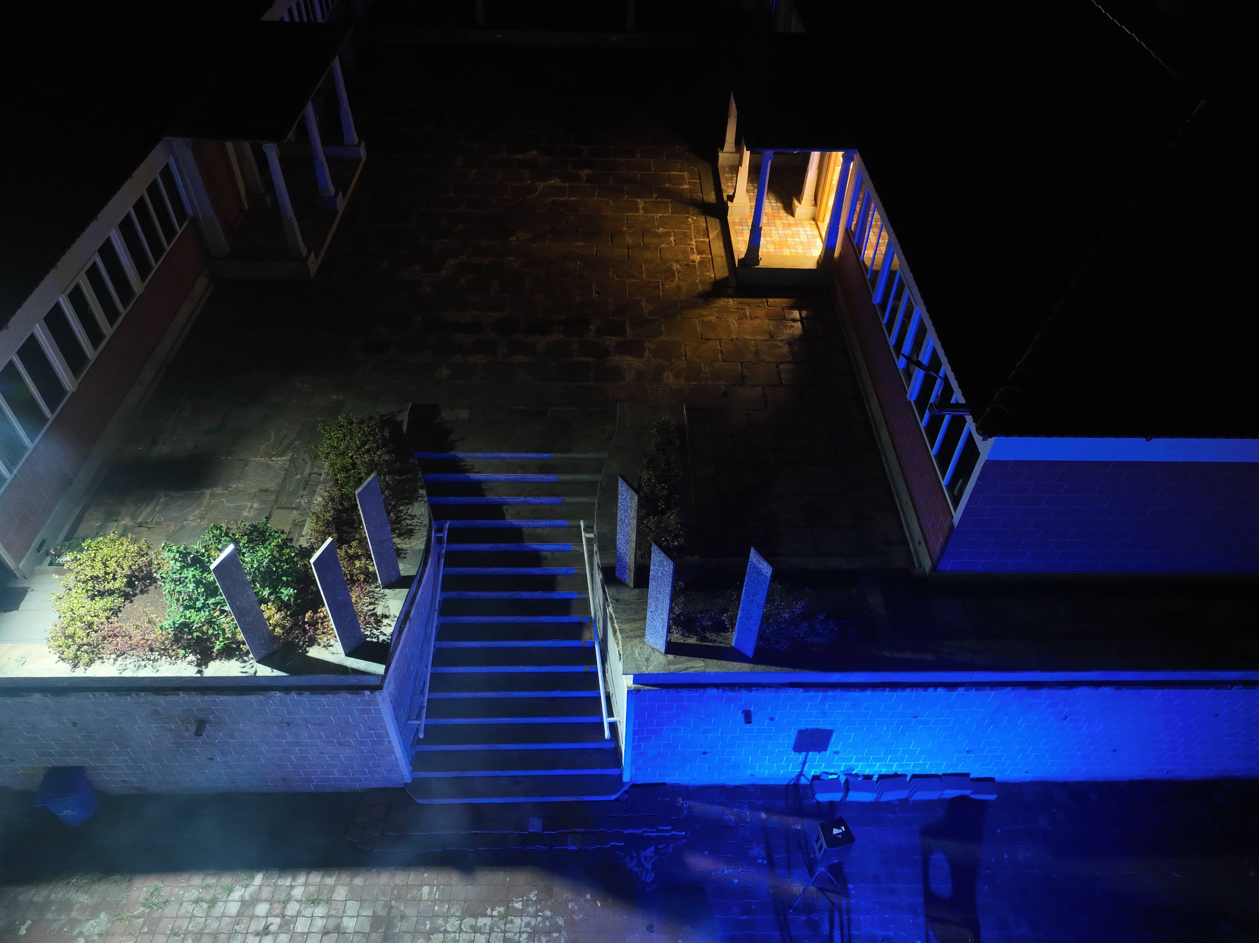 Night view of a luxury resort entrance with illuminated pathways, landscaped gardens, and elegant architecture. 