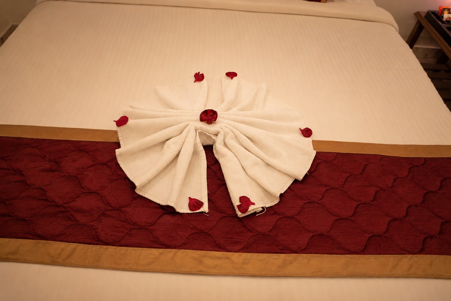Romantic towel art with rose petals on a luxury hotel bed for honeymoon and special occasion stays.