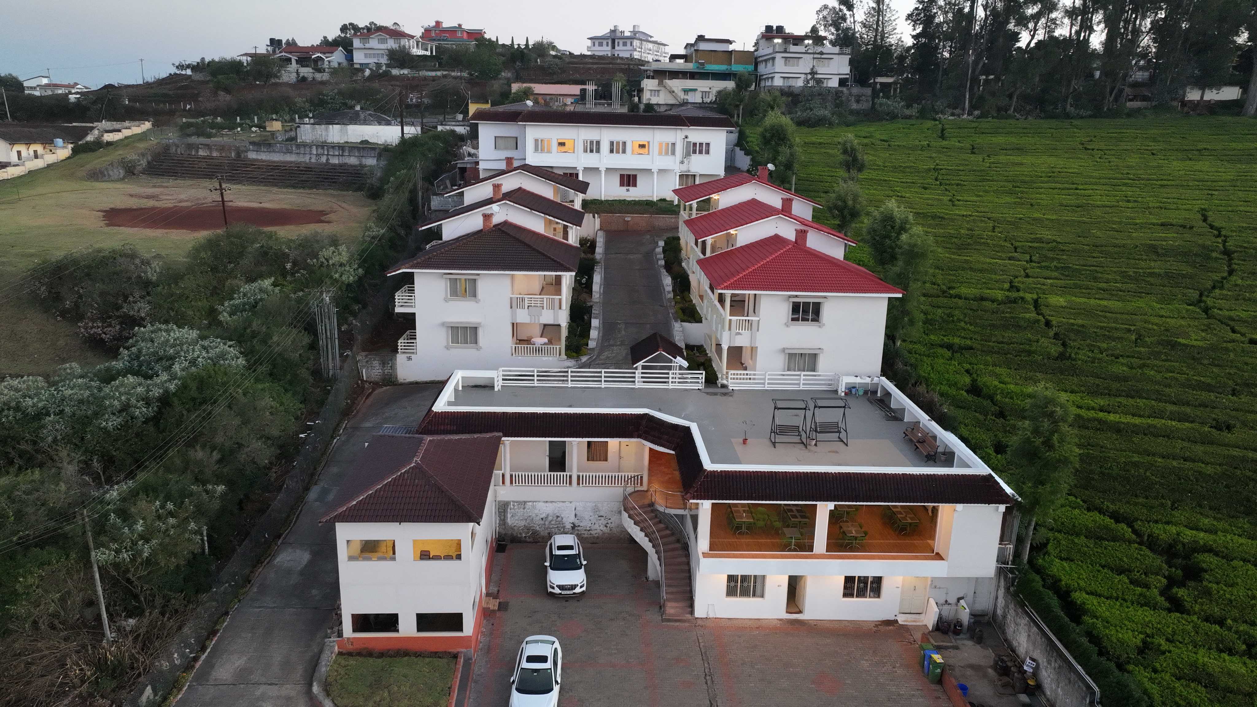 Drone view of a luxury hillside resort surrounded by tea plantations and scenic green landscapes. 